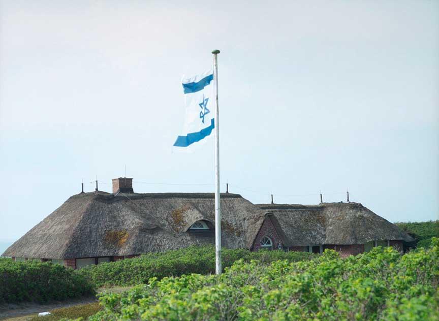 Israeli flag in front of a thatched roof