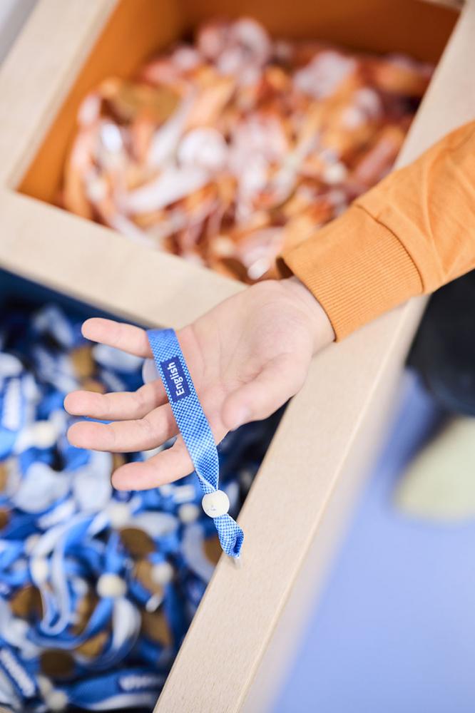 Child hand grips a blue ribbon with the inscription "English".