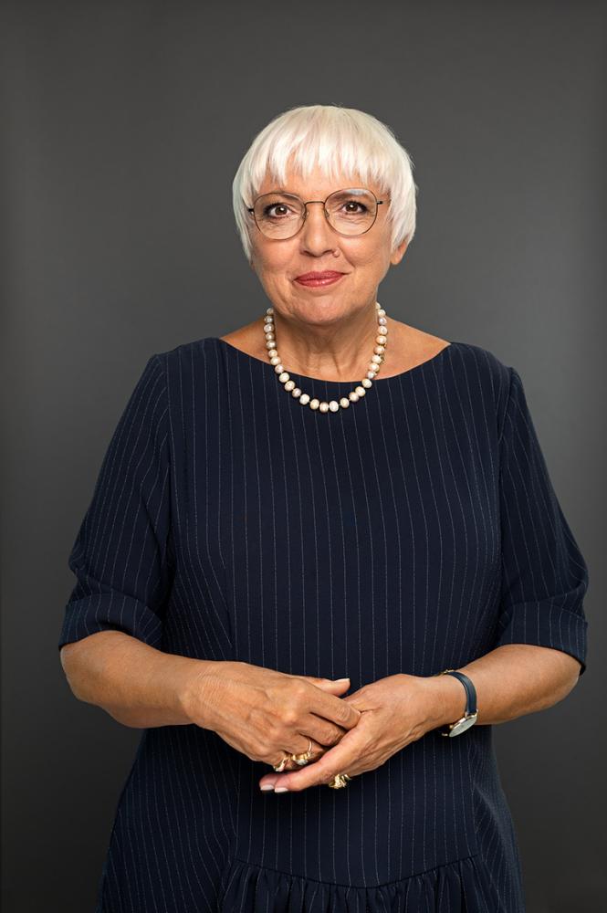 Portrait of Claudia Roth in black dress with white chain. She looks friendly into the camera.