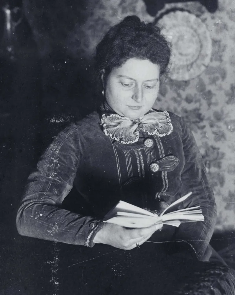 Porträt einer Frau, die ein Buch in der Hand hält und zu lesen scheint.