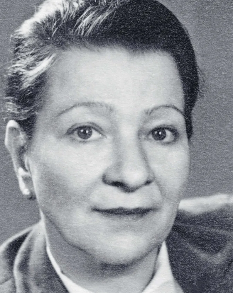Schwarz-Weiß-Fotografie eines Frauenkopfes. Die Person trägt kurze Haare und blickt direkt in die Kamera. 