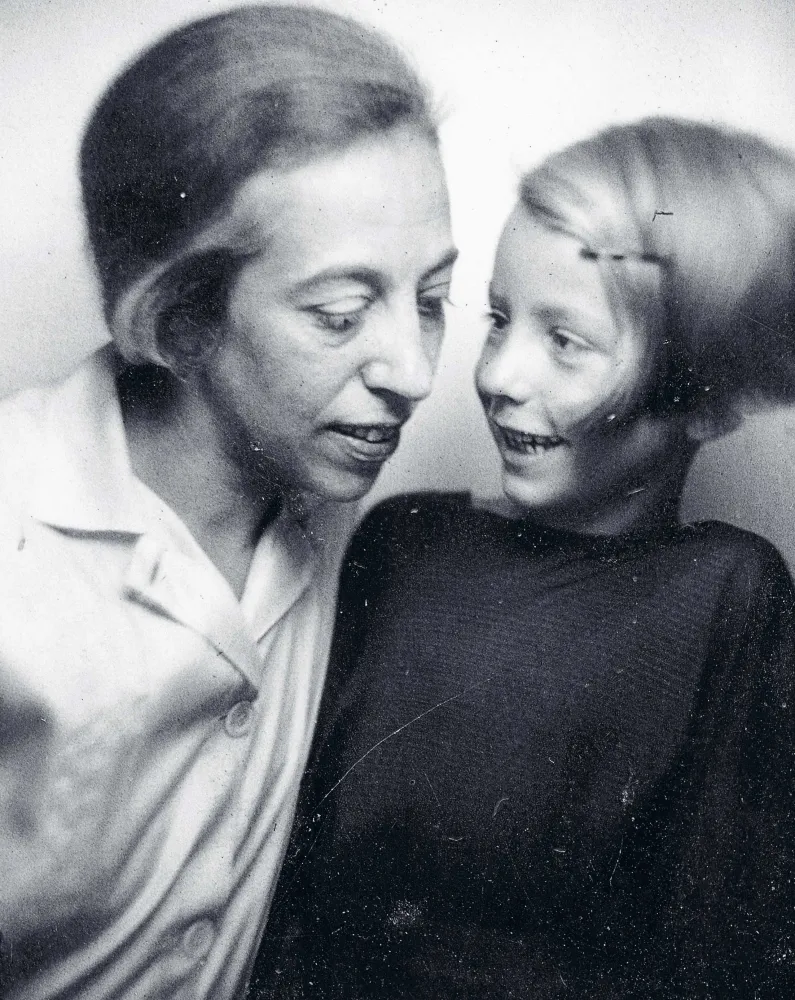  Sepia-colored portrait of a woman looking down; to her right is a child smiling at the woman.