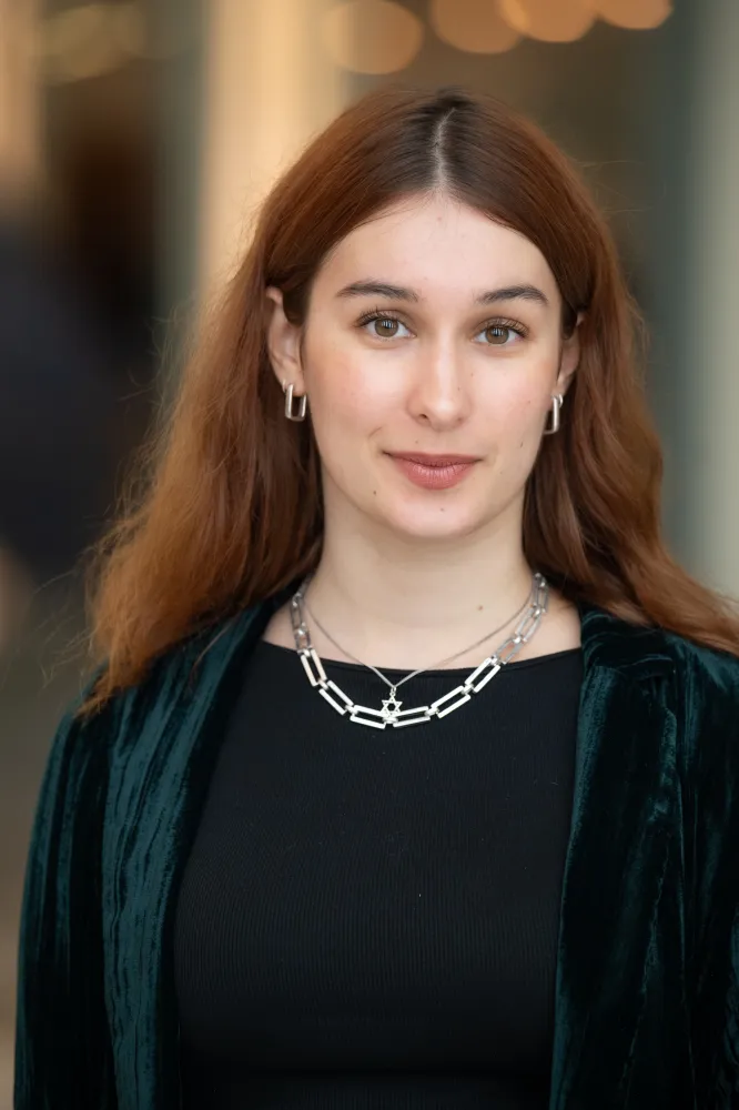 Portrait of a young woman with reddish-brown hair. She is wearing a necklace. 
