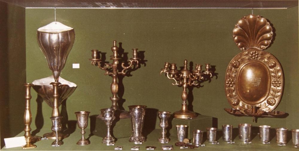 Foto einer Ausstellungsvitrine mit Judaica-Objekten vor grünem Hintergrund