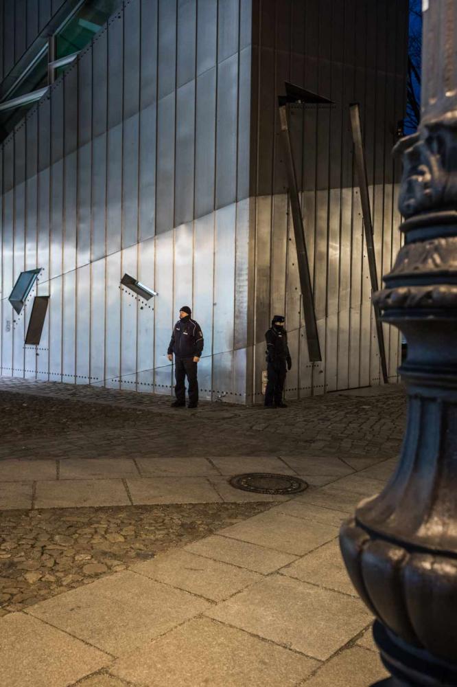 A policeman and a policewoman stand in front of the museum, looking in different directions. 