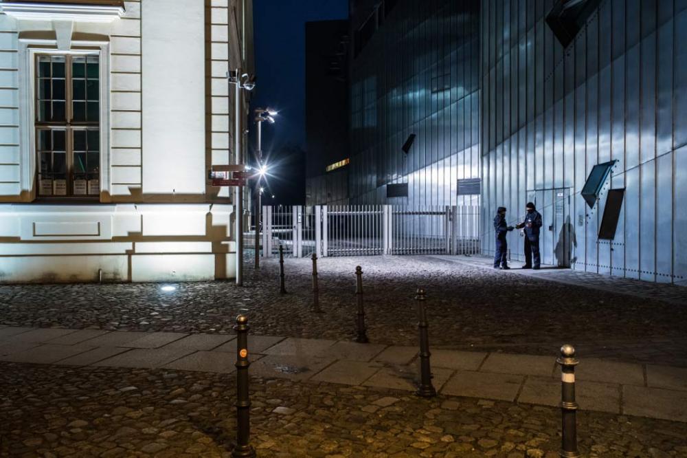 Two policewomen standing in front of the Libeskind-Building at night, talking. 