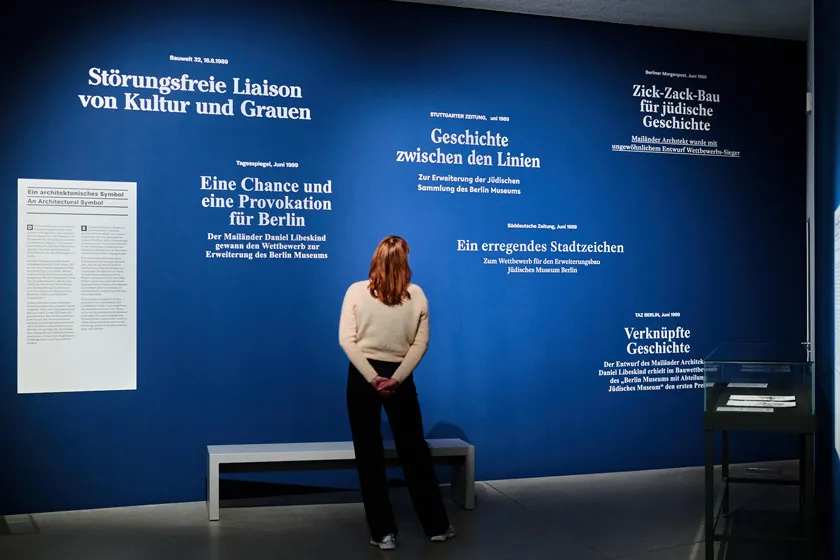 A person standing in front of a wall with text, reading them.