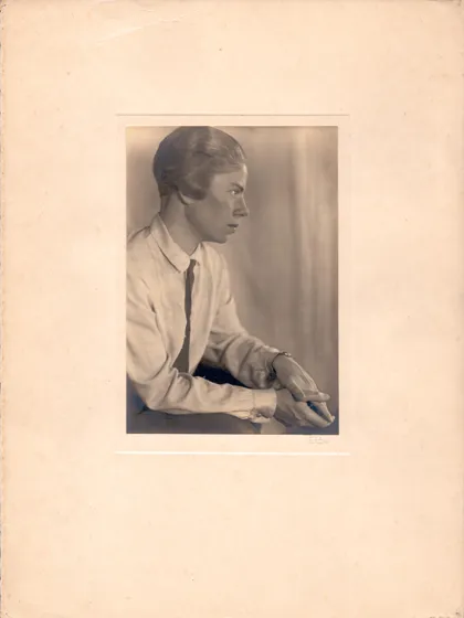  Sepia-colored portrait of a woman with ear-length hair in profile. She is wearing a shirt and tie.