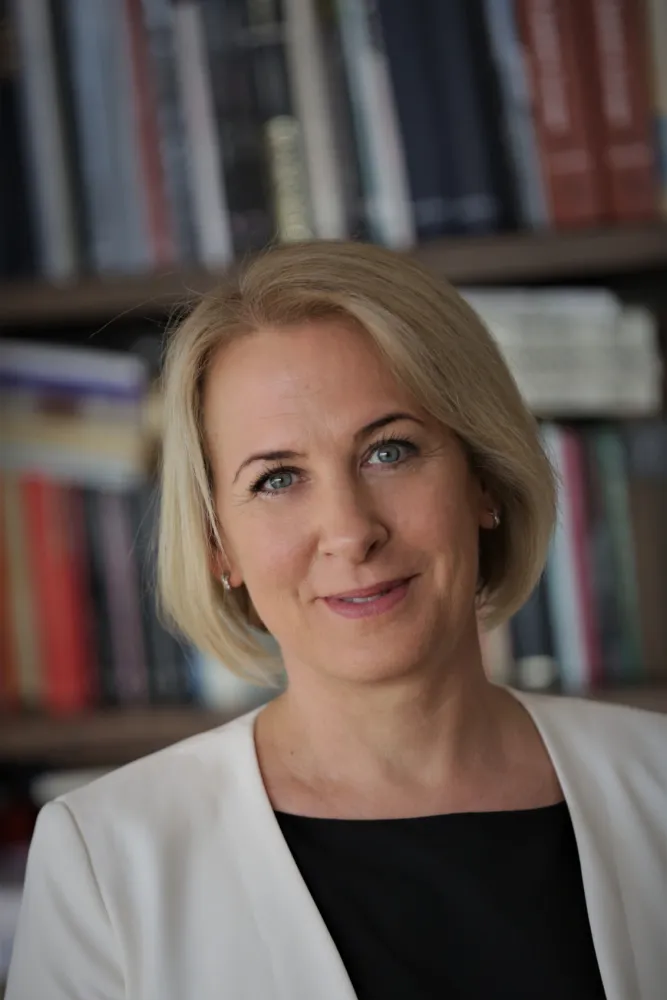 A woman with a blonde bob smiles at the camera.
