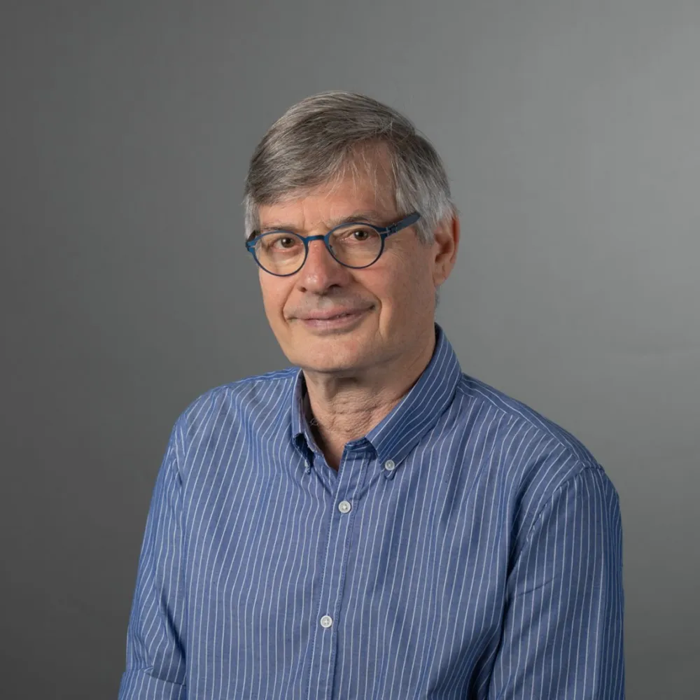 A man wearing glasses looks friendly at the camera.