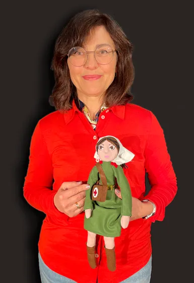 A woman with skinlong brown hair is holding a puppet in her hands.