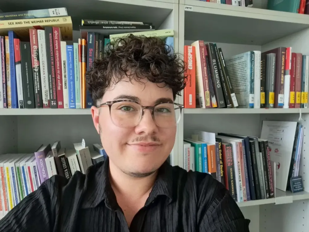 Eine Person mit Brille schaut freundlich in die Kamera.