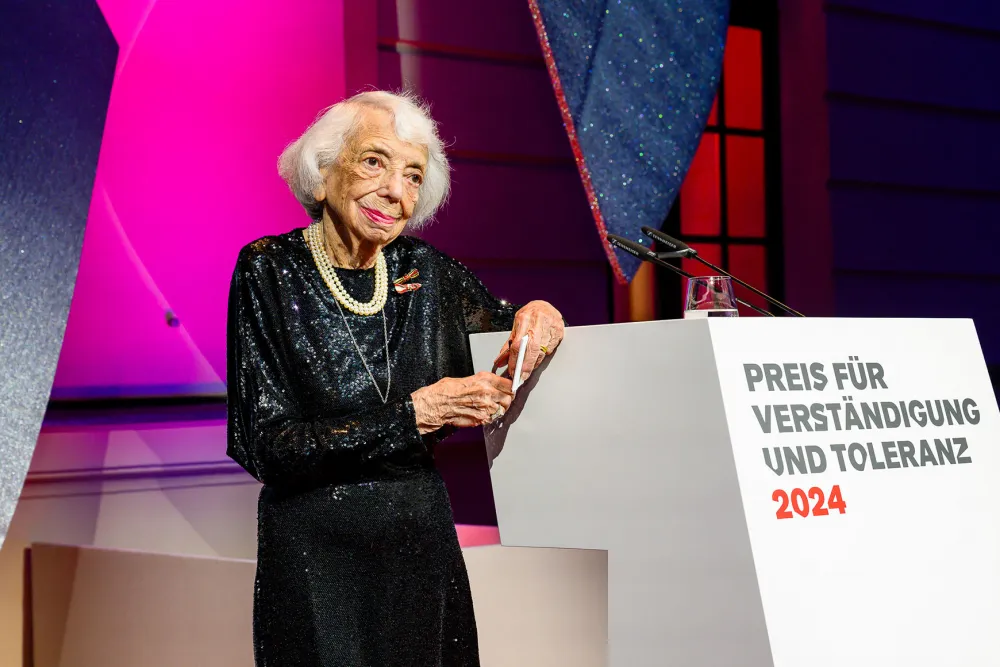A woman stands at a podium desk and smiles.
