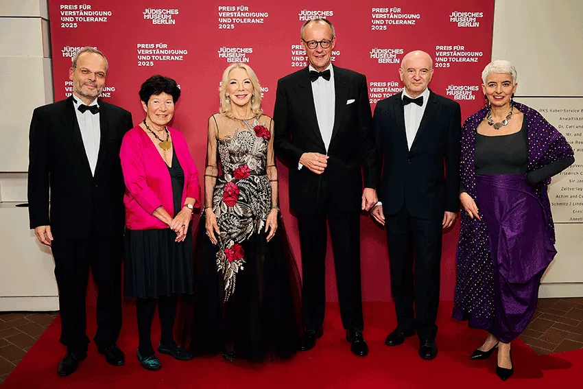 Eine Gruppe von sechs Personen in festlicher Kleidung. Sie stehen auf einem roten Teppich und schauen freundlich in die Kamera.