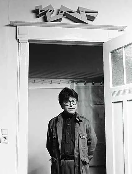 Das Bild zeigt einen jungen Mann, der in einem T&uuml;rrahmen steht. 