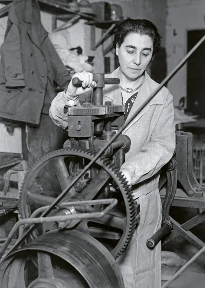  Black and white photograph of a woman at a machine.