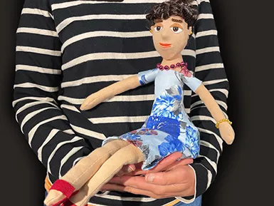 You can see the upper body of a person wearing a black and white striped sweater. She is holding a doll in her hands.