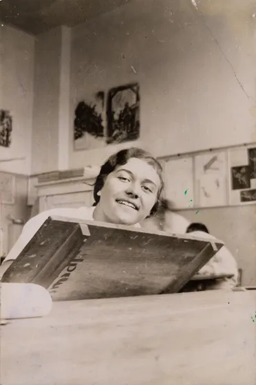  Photograph of a woman sitting behind a wooden table.
