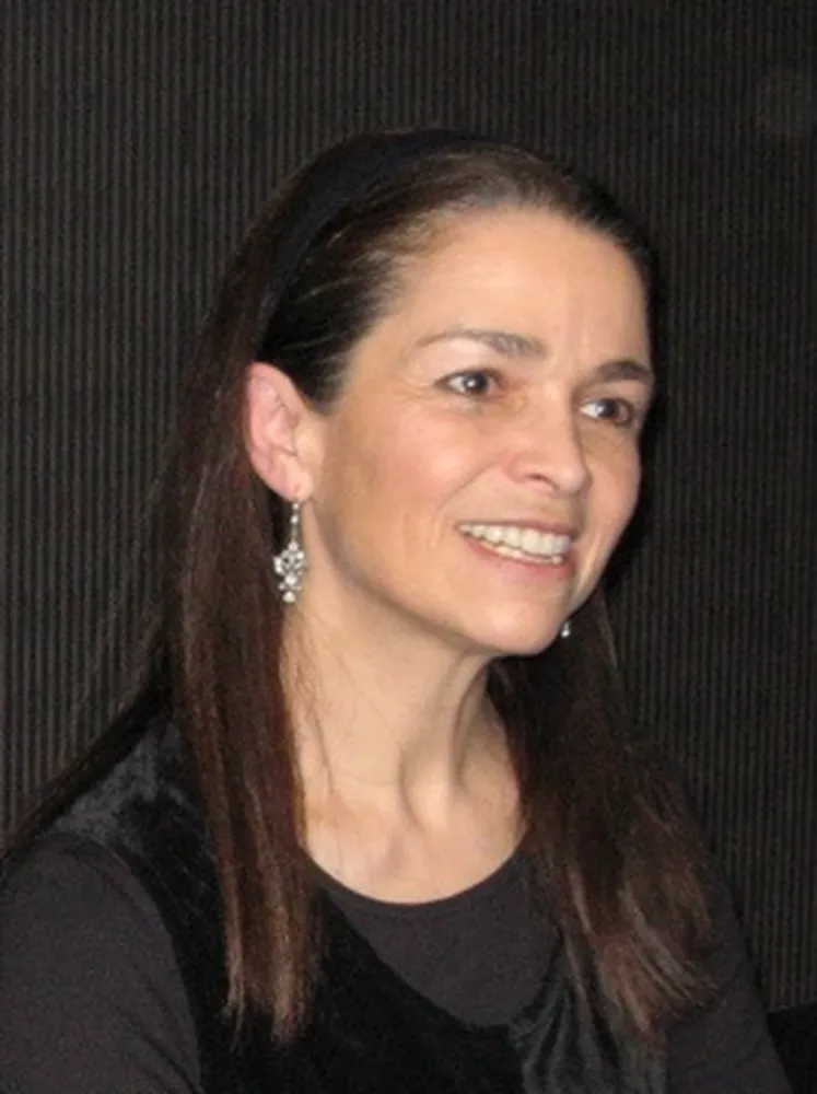 A woman looks to the side and smiles.