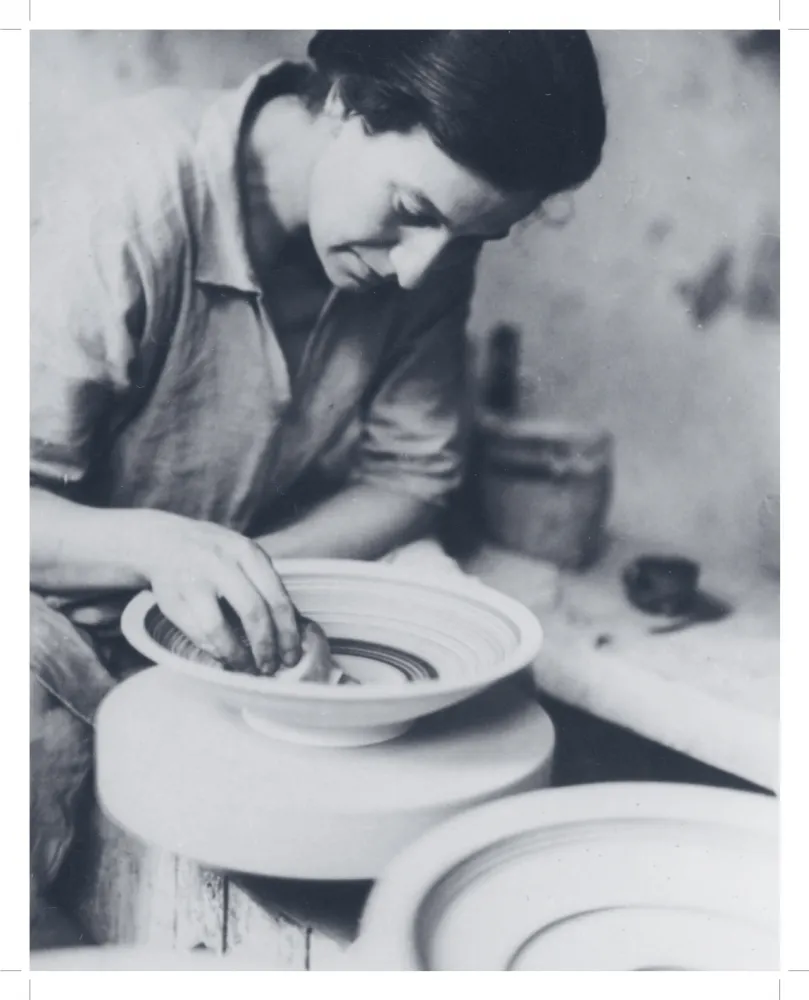 Schwarz-weiß-Fotografie einer Frau, die an einer Drehscheibe an einer töpferner Schale arbeitet.