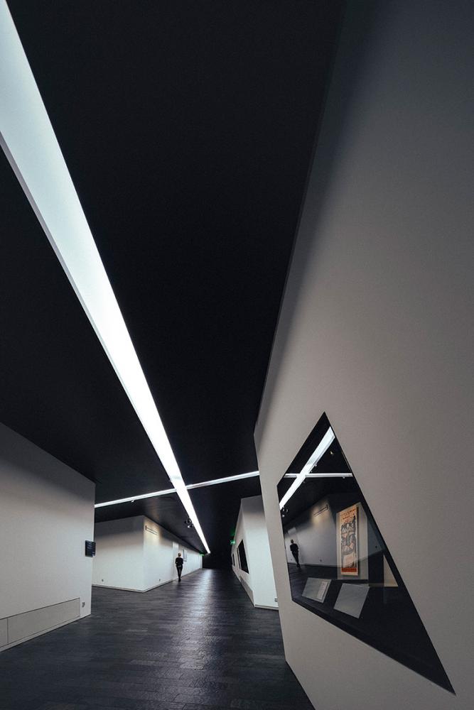 View into the Axis of the Holocaust at the Jewish Museum Berlin. The white walls, black floor and ceiling taper to the black door of the Holocaust Tower.