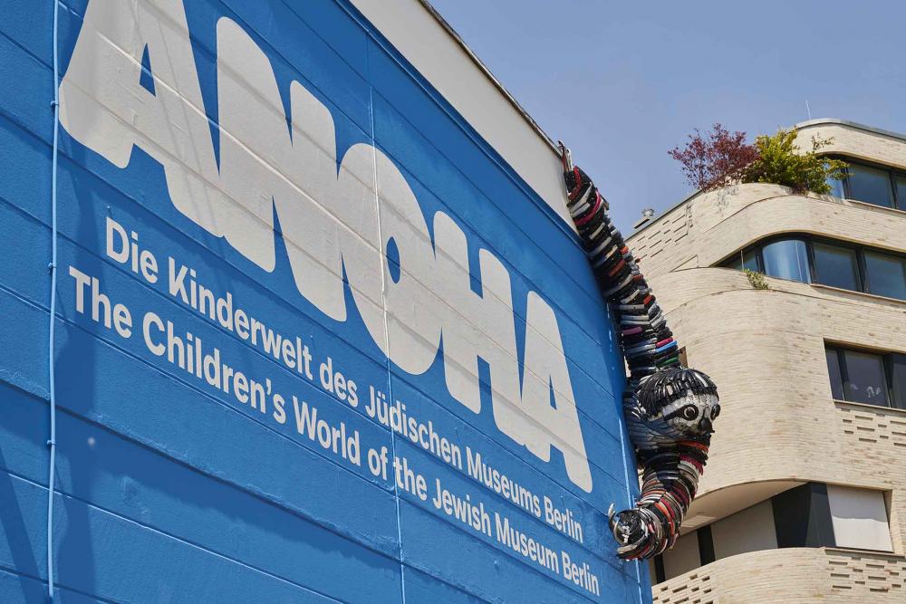 ANOHA-Schriftzug an einer Wand, an der ein Faultier aus Fahrradteilen hängt