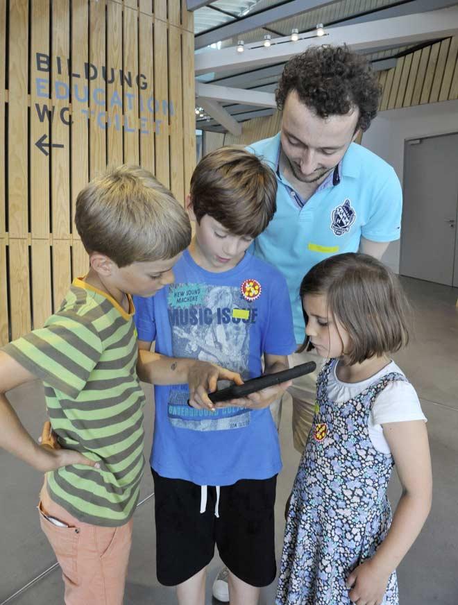 Drei Kinder und ein Mann schauen auf ein iPad