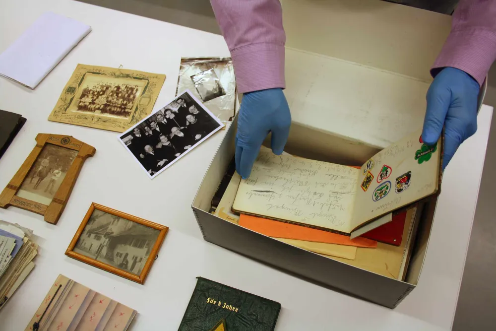Hands reach into a box of letters, photos and documents.
