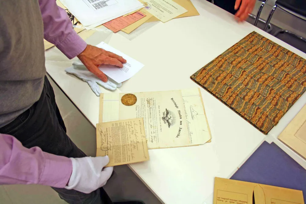 Hands hold old documents and letters.