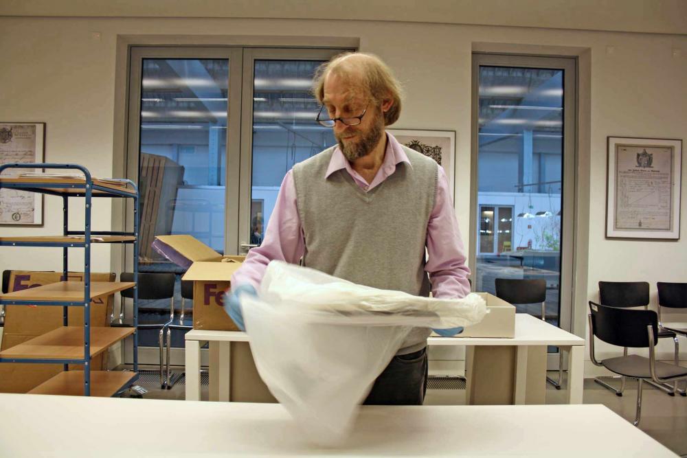 Ein Mann hält ein mit Papier umwickeltes Objekt.