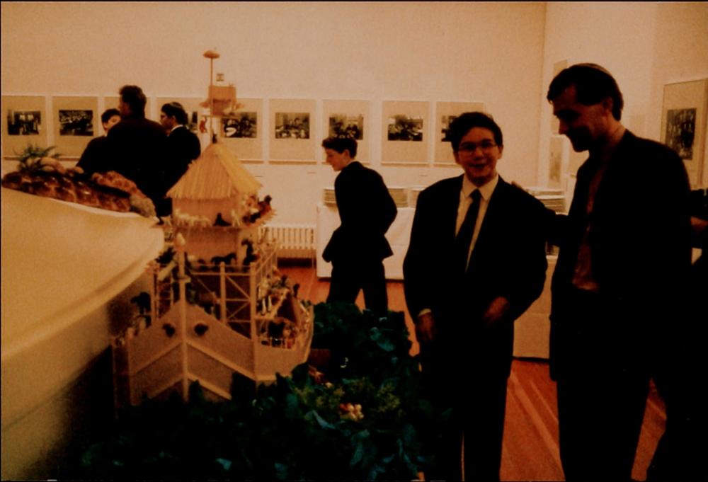 Exhibition room with a wooden ark in the center and people in the background. A boy in a suit and a man in a kippah stand next to the ark.