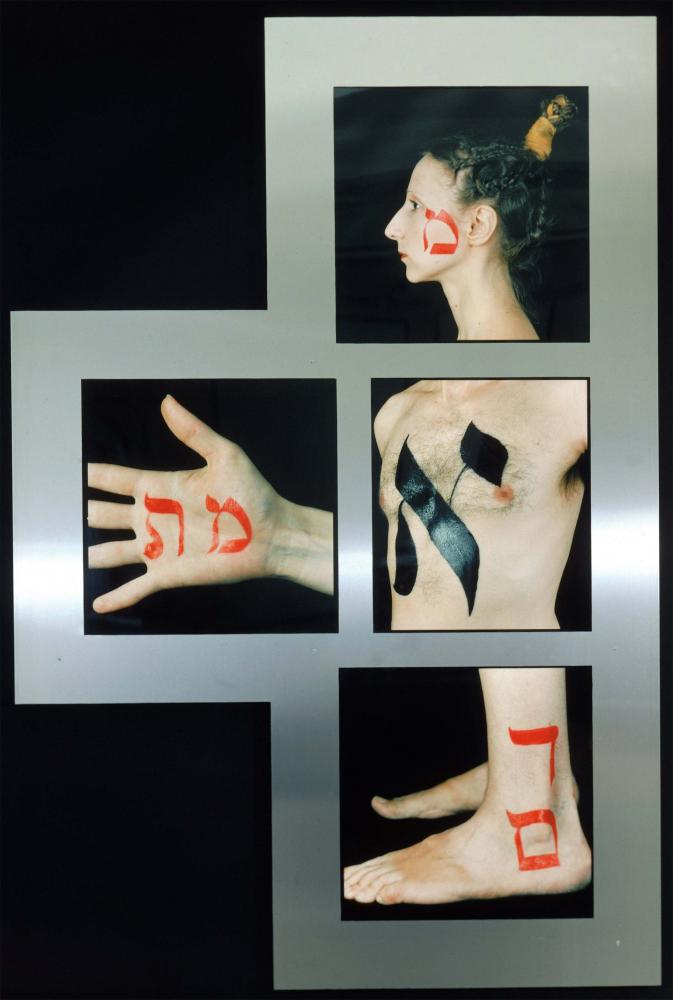 Four photographs on a metal plate: a woman's head, a men's torso, a hand, a pair of feet. On each photo, there is a Hebrew letter painted onto a part of the body.