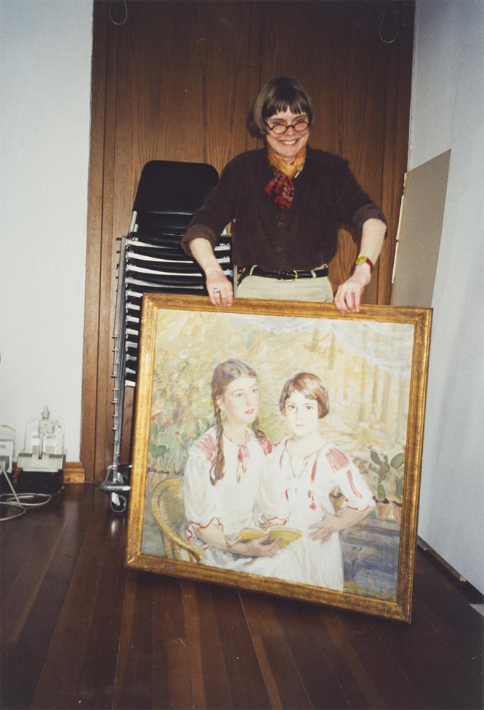 A woman holds the painting by Sabine Lepsius in front of her
