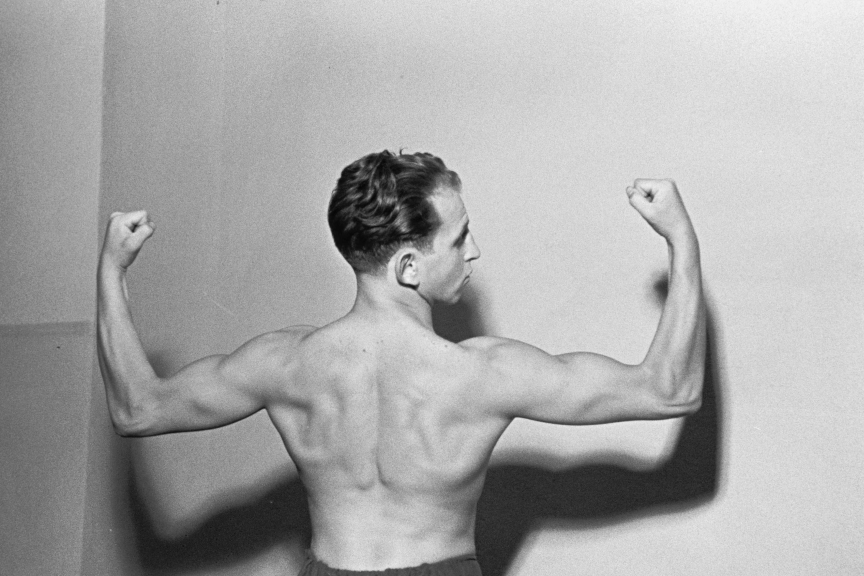 Portrait of a boxer . Photographed from a back view, he presents his upper body musculature. Head slightly bent back.