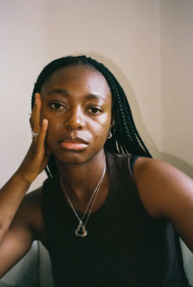 A woman is leaning on her hand and looking at the camera.
