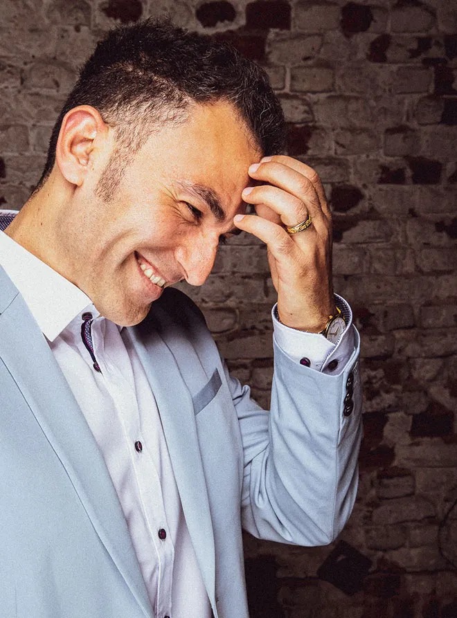 A man grabs his head and grins.