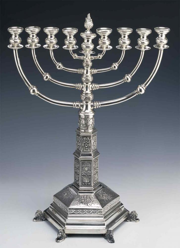 With its eight branches pointing in two directions, this silver Hanukkah menorah is an imitation of the original menorah in the Temple of Jerusalem. The richly ornamented base is held up by six lions.