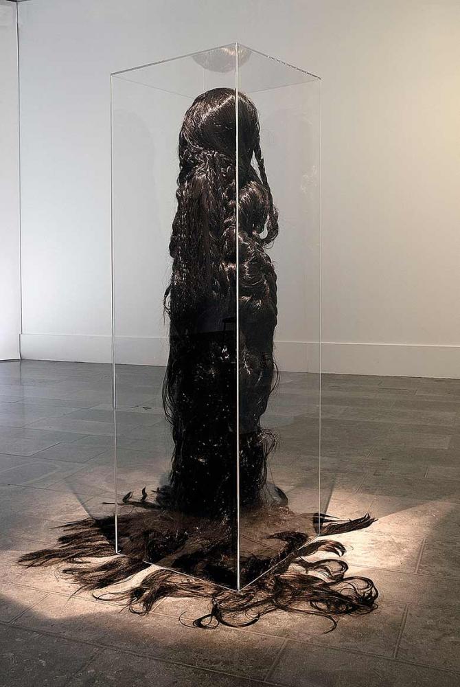 Life-sized sculpture of a figure with dark, floor-length hair