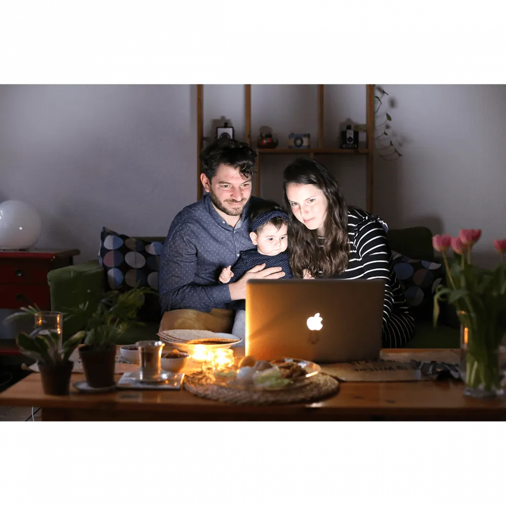 A man, a child and a woman sitting in front of a laptop
