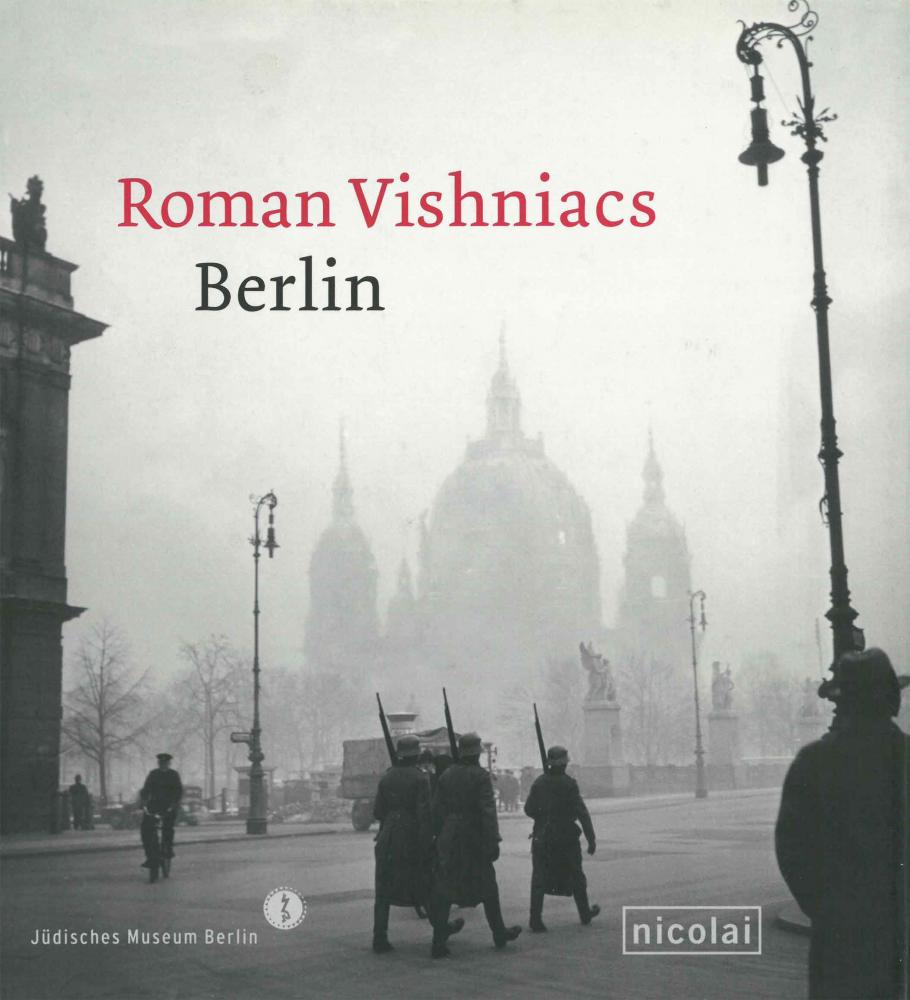 Cover of the catalog for the exhibition “Roman Vishniac’s Berlin”, historical black and white photograph of a small group of troops wearing large coats marching on a foggy day.