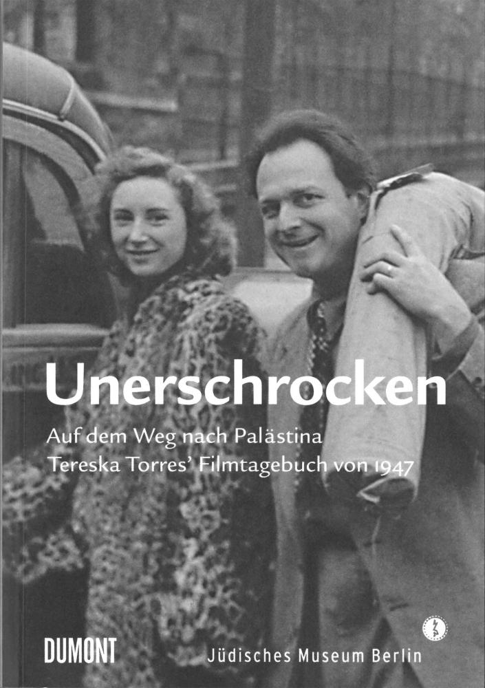 Book cover of “Unerschrocken”: black and white photograph of a young man and a young woman standing next to each other, both smiling. The man is carrying something over his shoulder that looks like a rolled up carpet.