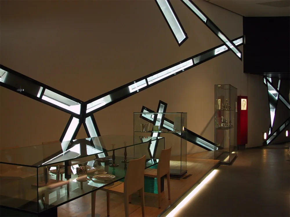Plates and silverware are displayed in a glass case in the permanent exhibition