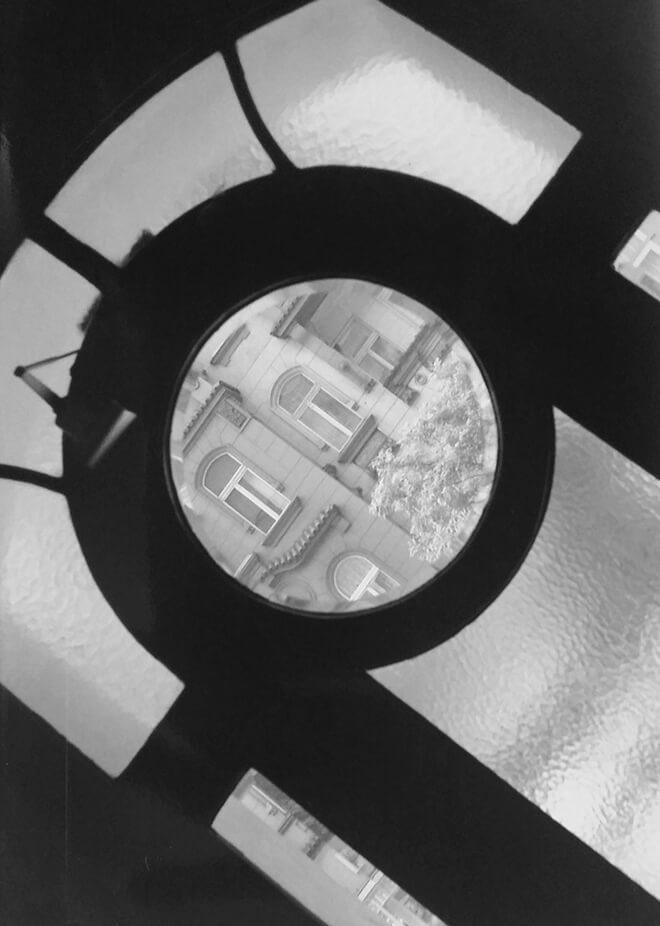 Black-and-white photograph: View of the buildings opposite through a transom window