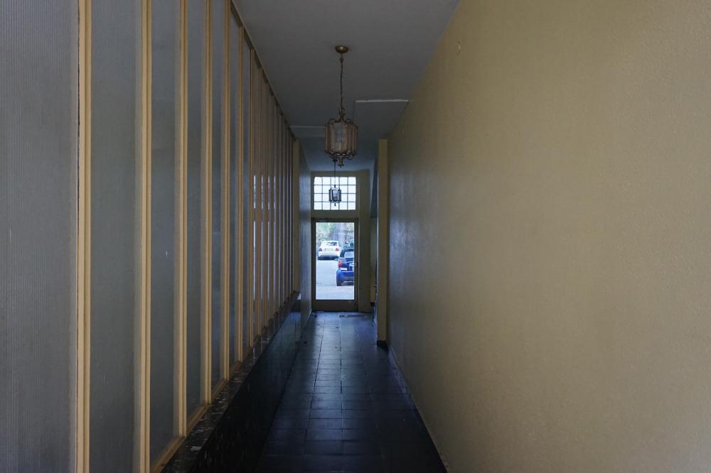 Color photo: narrow residential hallway with glass door to courtyard