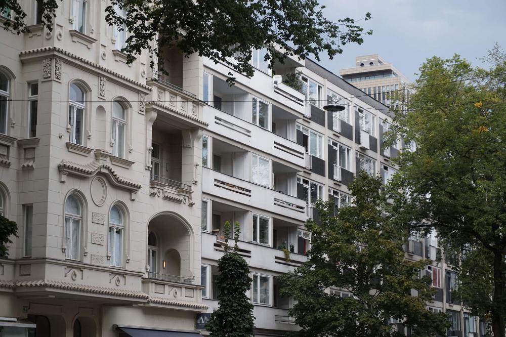 Farbfoto: Fassaden eines Berliner Altbaus und eines Nachkriegsbaus, mit Bäumen