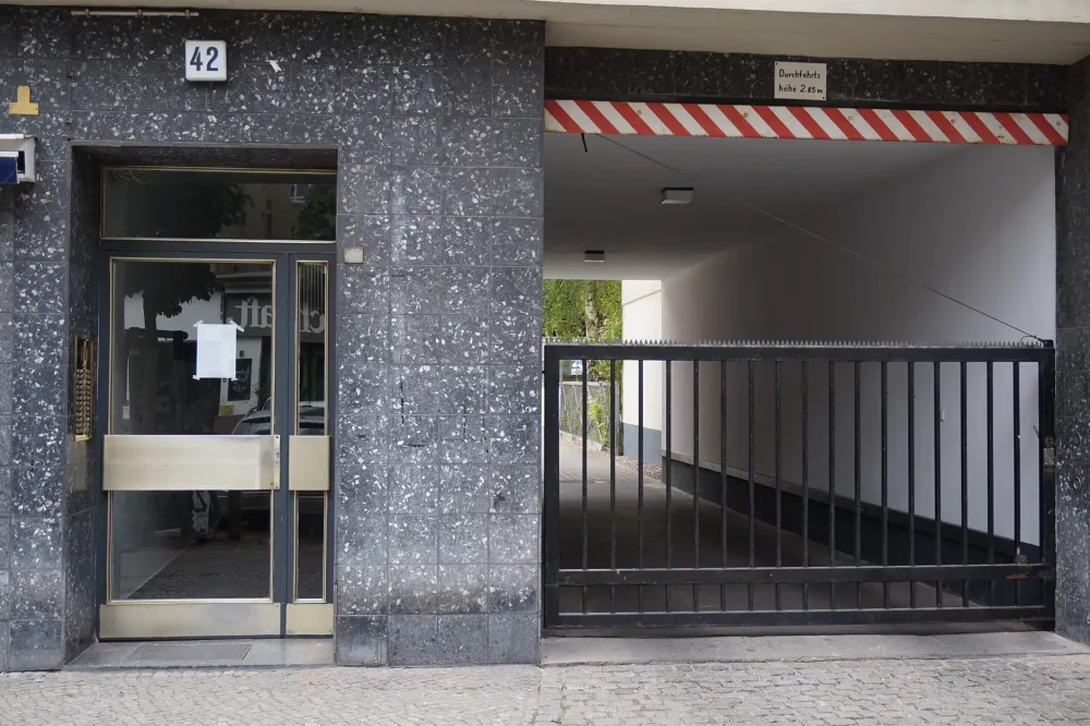 Color photo: Glass front door with address number “42” and entrance for cars