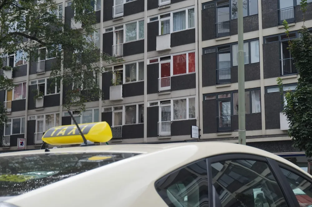 Color photo: View of a Berlin postwar building with a taxi in the foreground