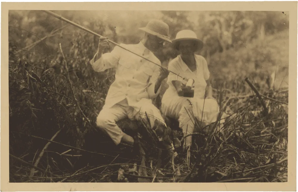 Historische Schwarz-Weiß-Fotografie  von zwei Forschern die im Gras sitzen.