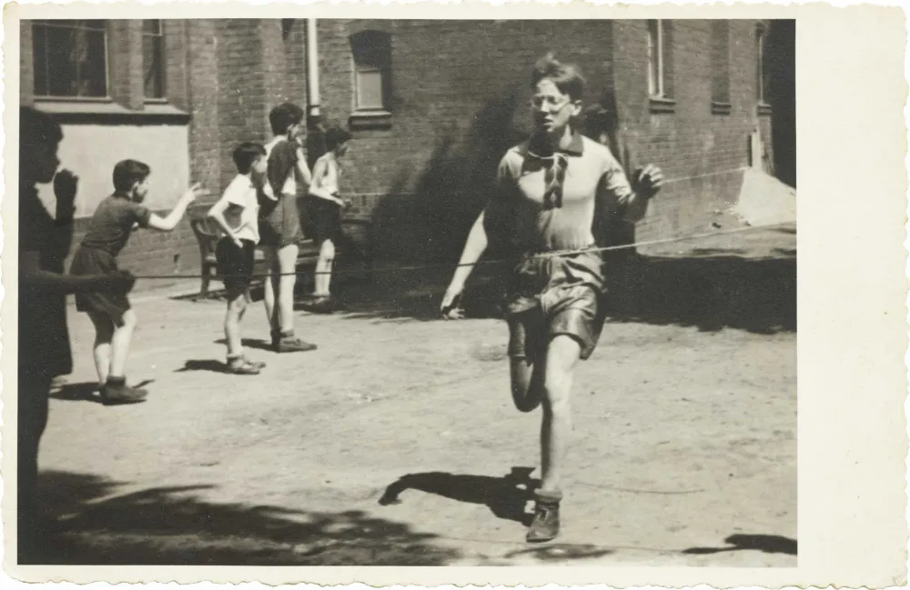 In the foreground of the picture you can see a running boy, who is about to reach the finish line, boys watching in the background (black and white photo).