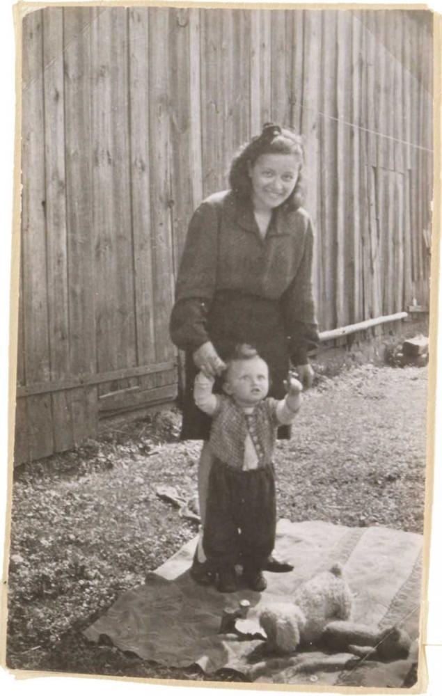 The photo shows a toddler held by a woman’s hands (black and white photograph).